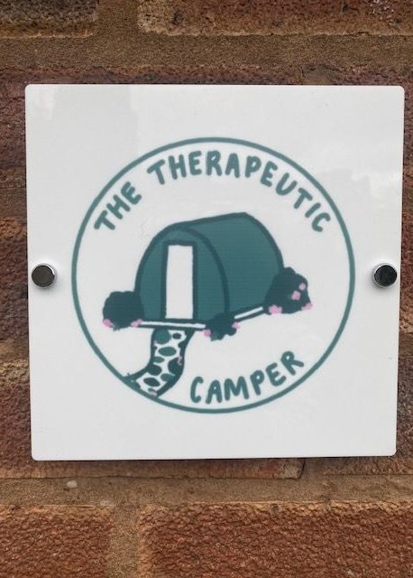 Sign for "The Therapeutic Camper" featuring a tented camper illustration.