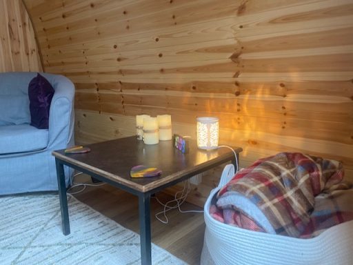 Cozy interior with a sofa, table, candle, and a blanket in a wooden setting.