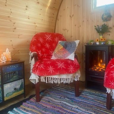 Cosy interior with two chairs, a heater, and a colourful rug in a wooden cabin.